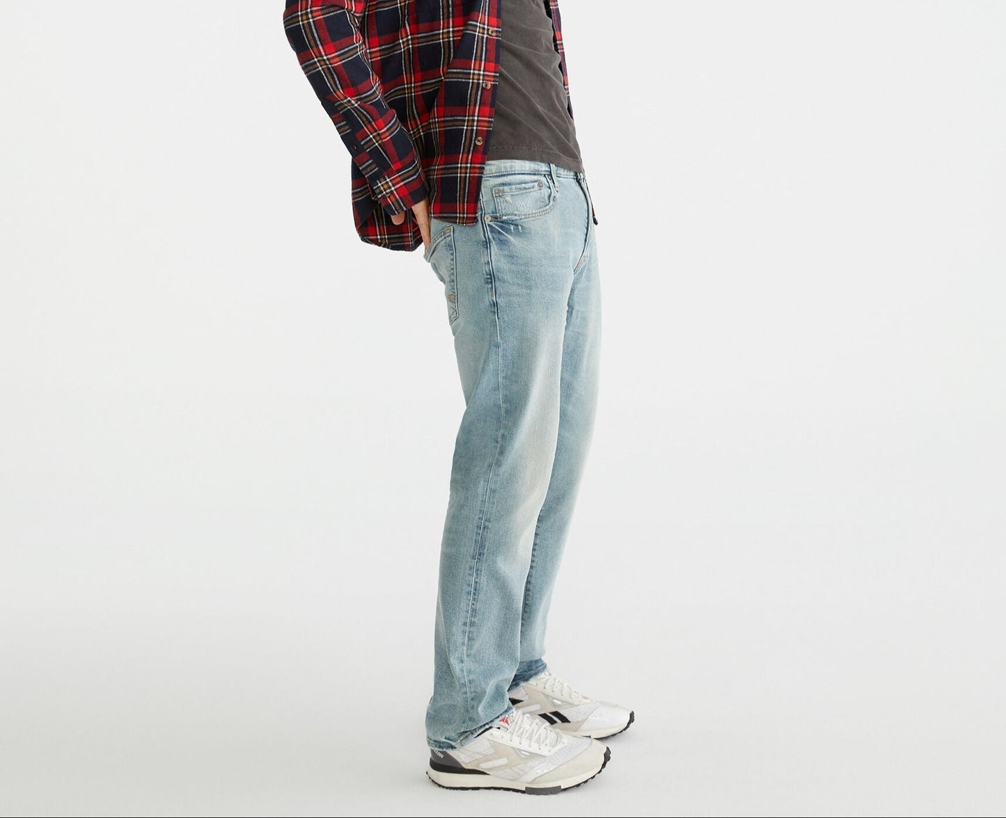 Person wearing a plaid shirt and jeans on a white background