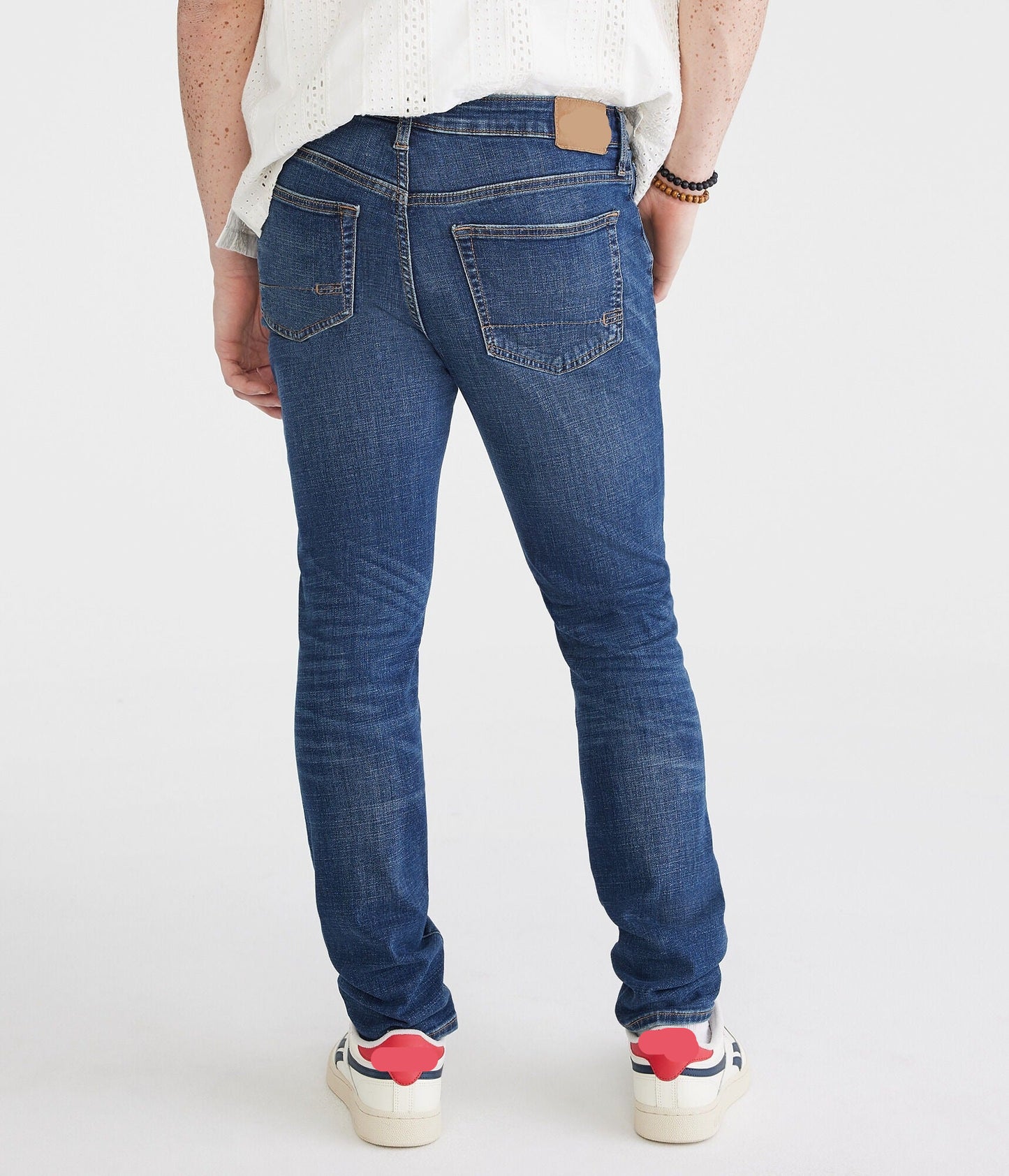 Person wearing blue jeans and colorful sneakers on a white background