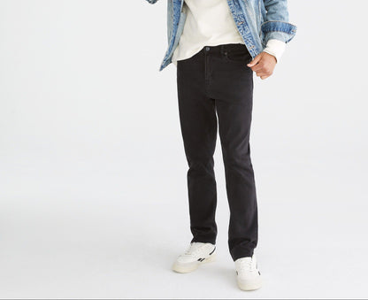 Man wearing a denim jacket, white t-shirt, black jeans, and white sneakers on a white background