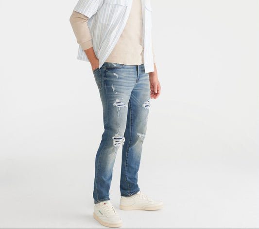 Person wearing a white shirt, beige t, and blue jeans on a white background