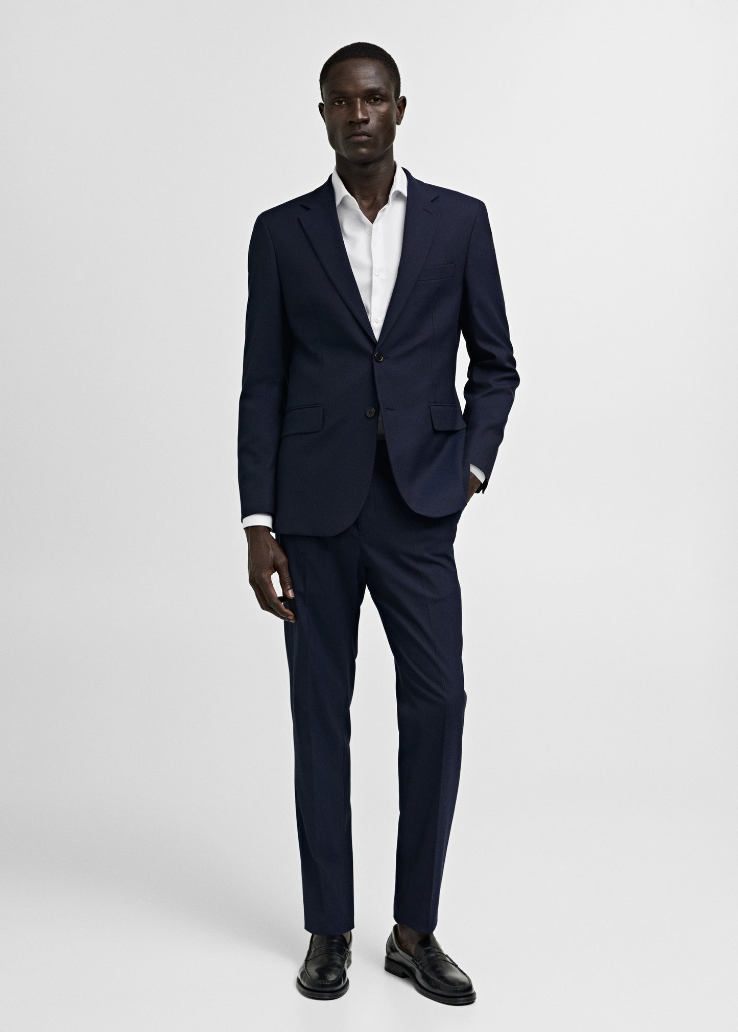 Man wearing a navy suit with a white shirt on a light gray background